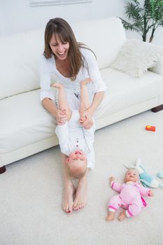 Mother playing with a baby while sitting on a sofa in living room