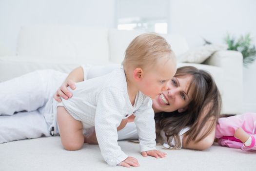 Baby on all fours next to his mother in living room