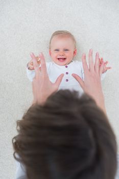 High view of a baby lying on back while playing in living room