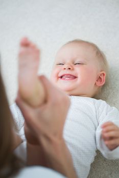 Mother raising the leg of a baby in living room