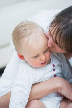 Mother kissing a baby in living room