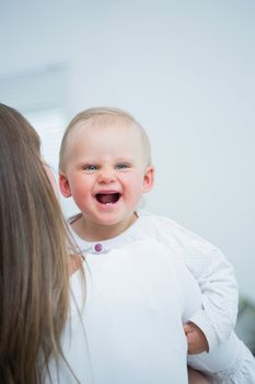 Mother holding a baby on his arms in living room