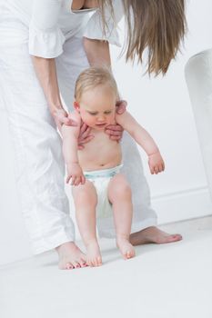 Mother holding a baby under his arms in living room