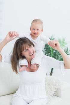 Baby sitting on shoulders of his mother in living room