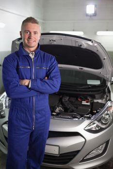 Mechanic standing while looking at camera in a garage