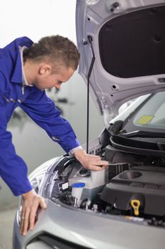 Concentrated mechanic looking at an engine in a garage