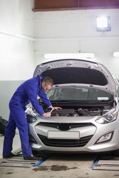 Mechanic looking at the car engine in a garage