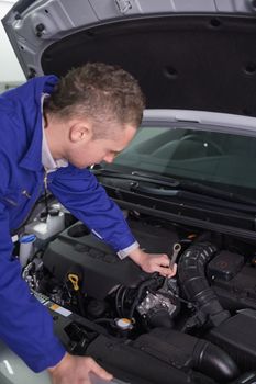 Mechanic repairing an engine with a spanner in a garage
