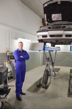 Mechanic standing next to a car in a garage