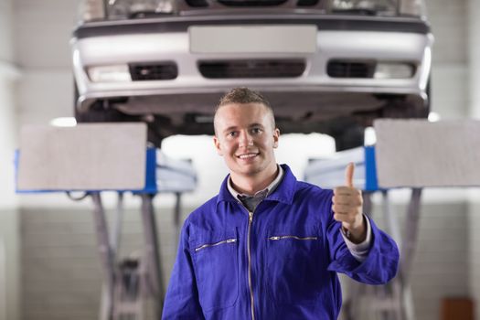 Mechanic standing with thumb up in a garage