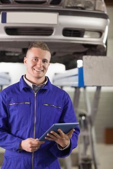 Smiling mechanic holding a tablet computer in a garage
