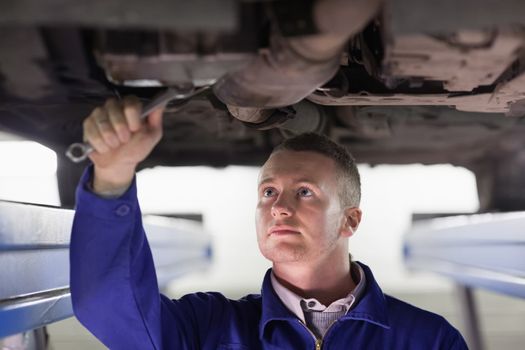 Mechanic repairing a car with a spanner in a garage