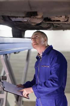 Mechanic looking at the below of a car in a garage