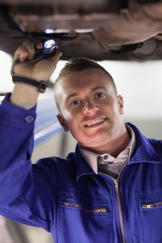 Mechanic illuminating the below of a car in a garage