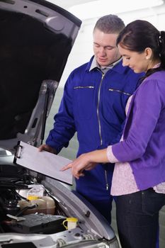 Woman looking at the clipboard next to a car in a garage