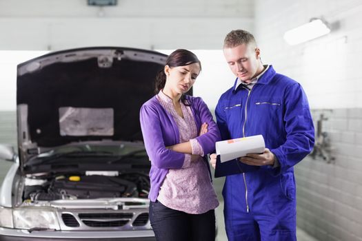 Mechanic showing a clipboard to a client in a garage