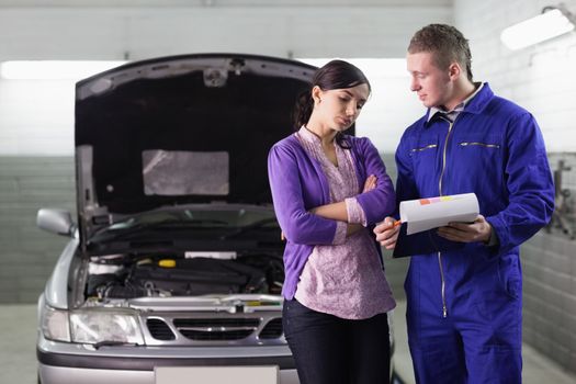Mechanic showing the quotation to a client in a garage