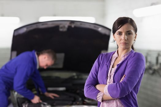 Woman looking at camera next to a car in a garage