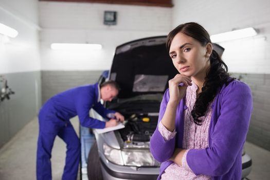 Thoughtful woman next to a mechanic in a garage