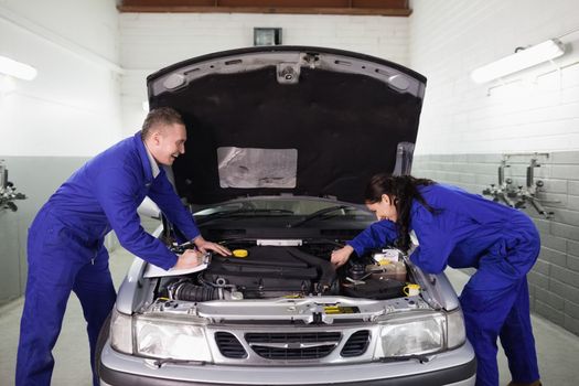 Mechanics examining a car engine in a garage