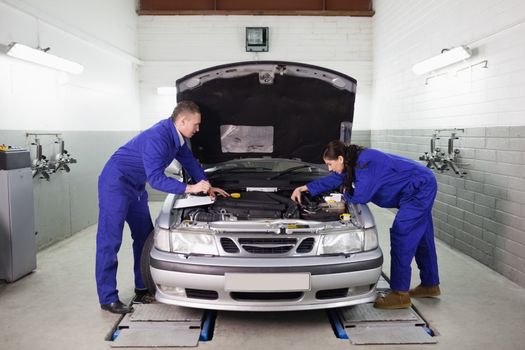 Mechanics looking at the engine in a garage