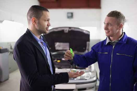 Mechanic giving car key to a man in a garage