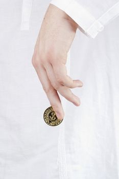 Close-up photograph of a golden coin between a man's fingers.