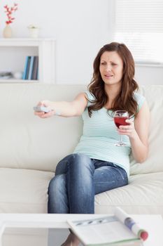 Woman pressing a remote control while sitting in a living room
