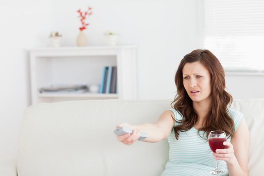 Woman sitting on a sofa while holding a glass of wine in a living room