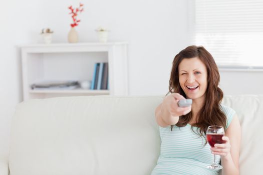 Smiling woman pressing a remote control in a living room
