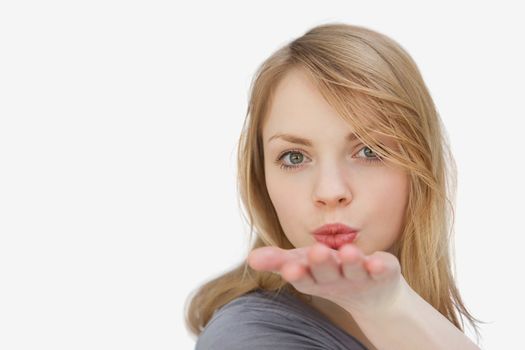 Blonde woman blowing on her hand against a white background