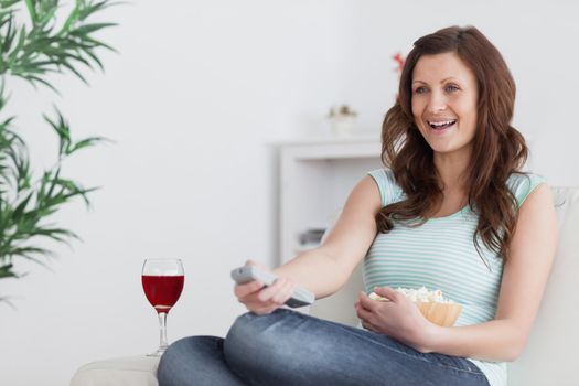 Woman smiling while pressing a remote control in a living room