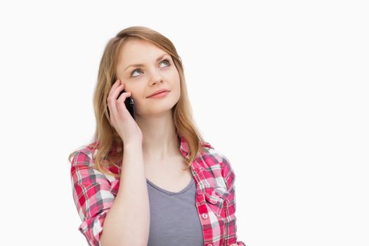 Woman looking up while holding a mobile phone against a white background