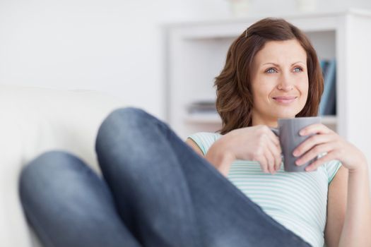 Woman looking away while holding a mug in a living room