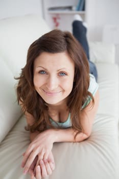 Smiling woman lying on the belly on a sofa in a living room