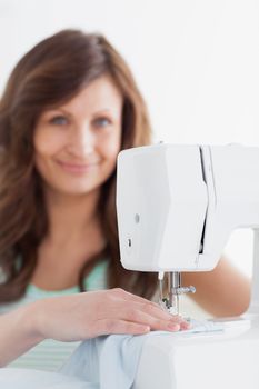 Woman using a sewing machine against a white background
