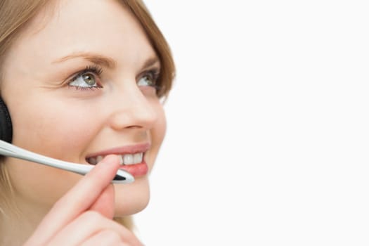 Woman with headset smiling while looking up against a white background