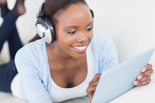 Black woman lying on front using a table computer in a living room