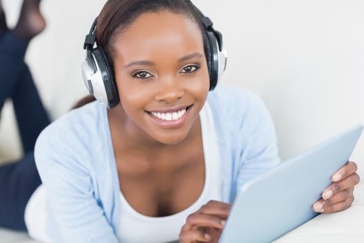 Black woman listening music while looking at camera in a living room