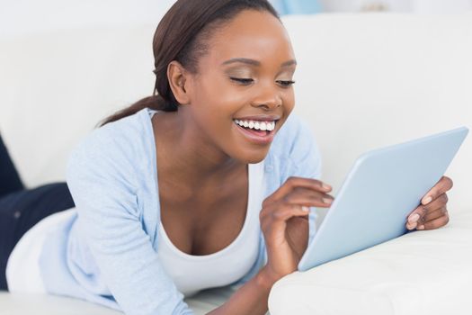 Black woman smiling while touching a tablet computer in a living room