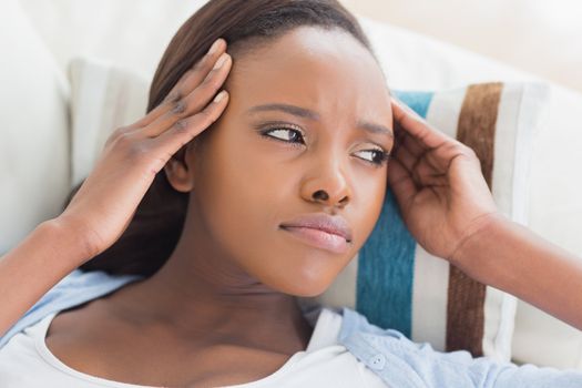 Black woman having pains on the head in a living room