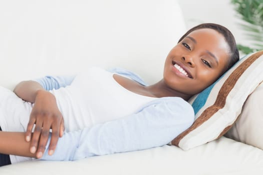Black woman lying on back on a sofa in a living room