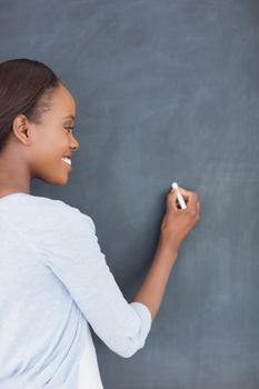 Black woman writing on a blackboard in a classroom