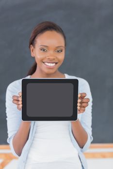 Smiling black woman holding a tablet computer in a classroom
