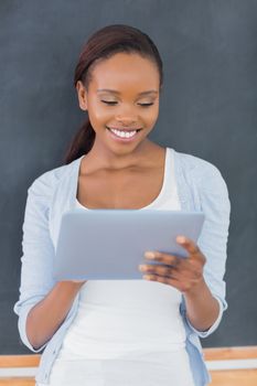 Front view of a black woman looking at a tablet computer in a classroom