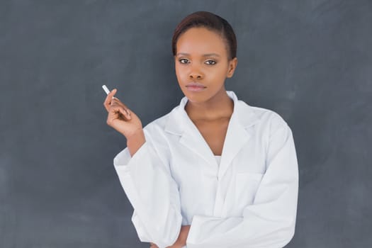 Teacher holding a chalk while looking at camera in a classroom