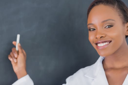 Teacher smiling while holding a chalk in a classroom