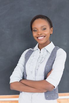 Teacher smiling next to a blackboard in a classroom