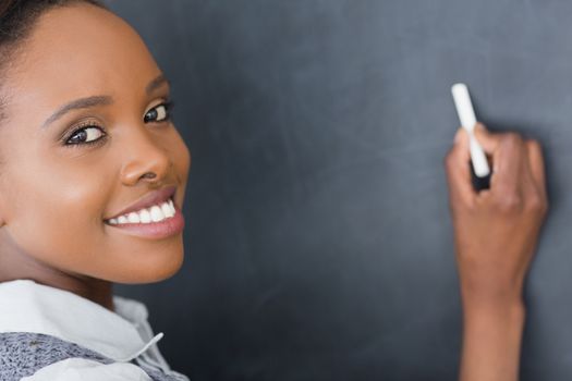 Close up of a teacher writing on a blackboard in a classroom