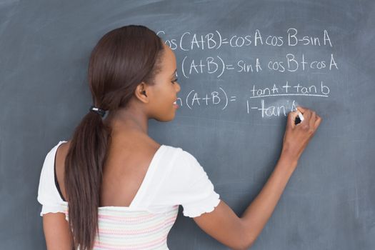 Black student writing on a blackboard in a classroom